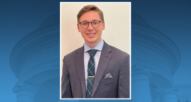 Photo of Andy Tomusiak, a young man in grey suit and blue tie